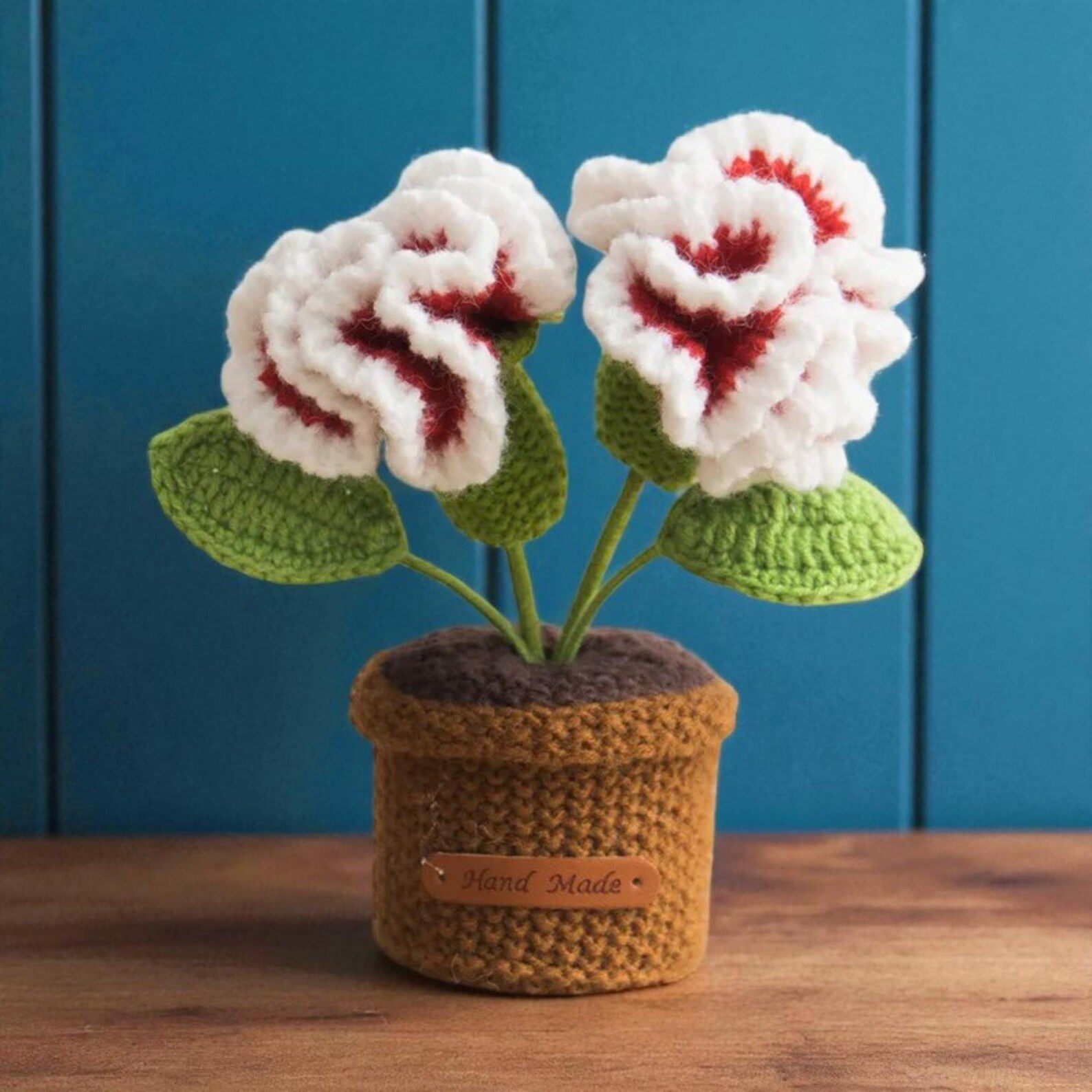 Crocheted flowers in a pot with a blue background