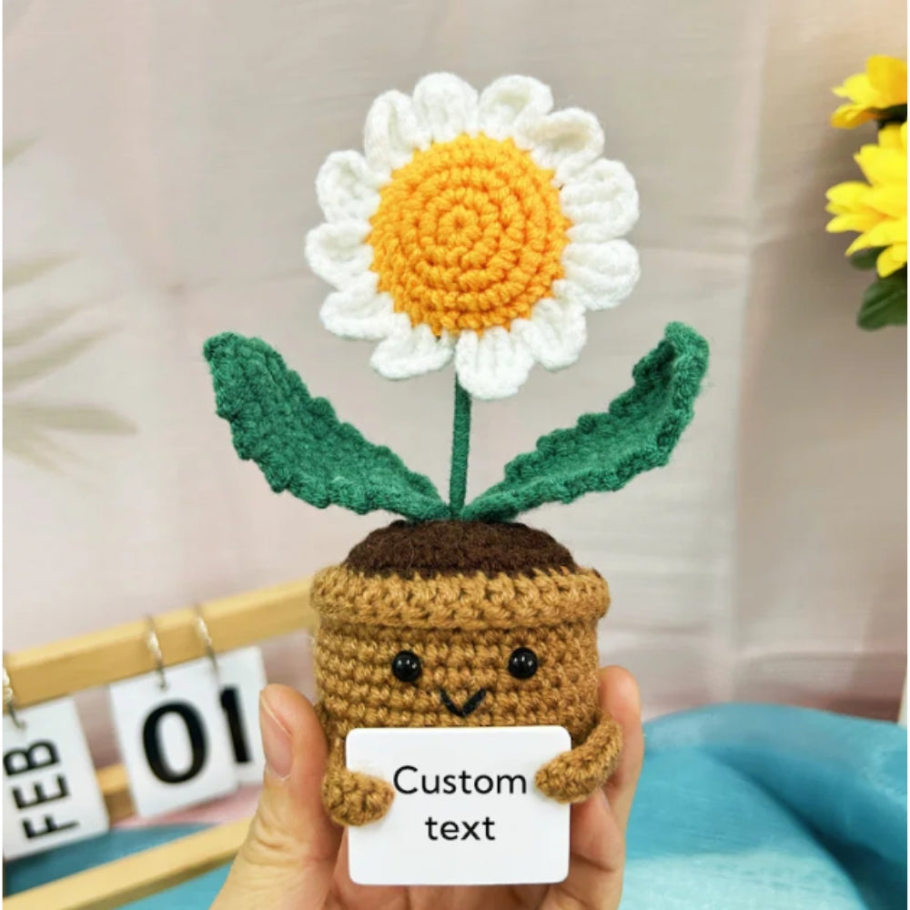 Handmade crochet flower in a pot held by a person with a white card for text.