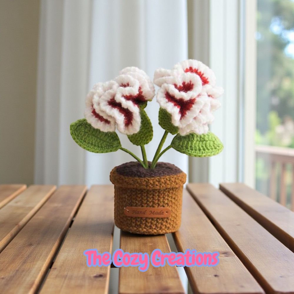 Crocheted potted plant on a wooden surface with 'The Cozy Creations' branding.