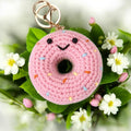 Pink crocheted donut keychain with sprinkles on a floral background