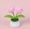 Knitted pink flowers in a white pot on a pink background