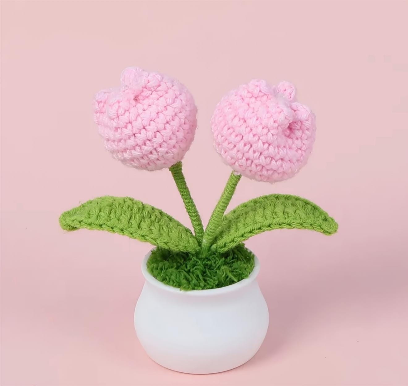 Knitted pink flowers in a white pot on a pink background