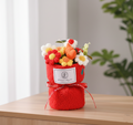 Decorative flower pot with colorful flowers and a red base on a wooden surface.