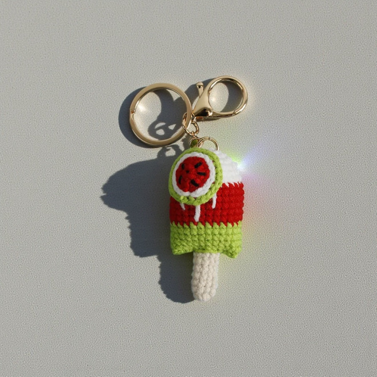 Crocheted ice cream keychain with watermelon design on a gray background