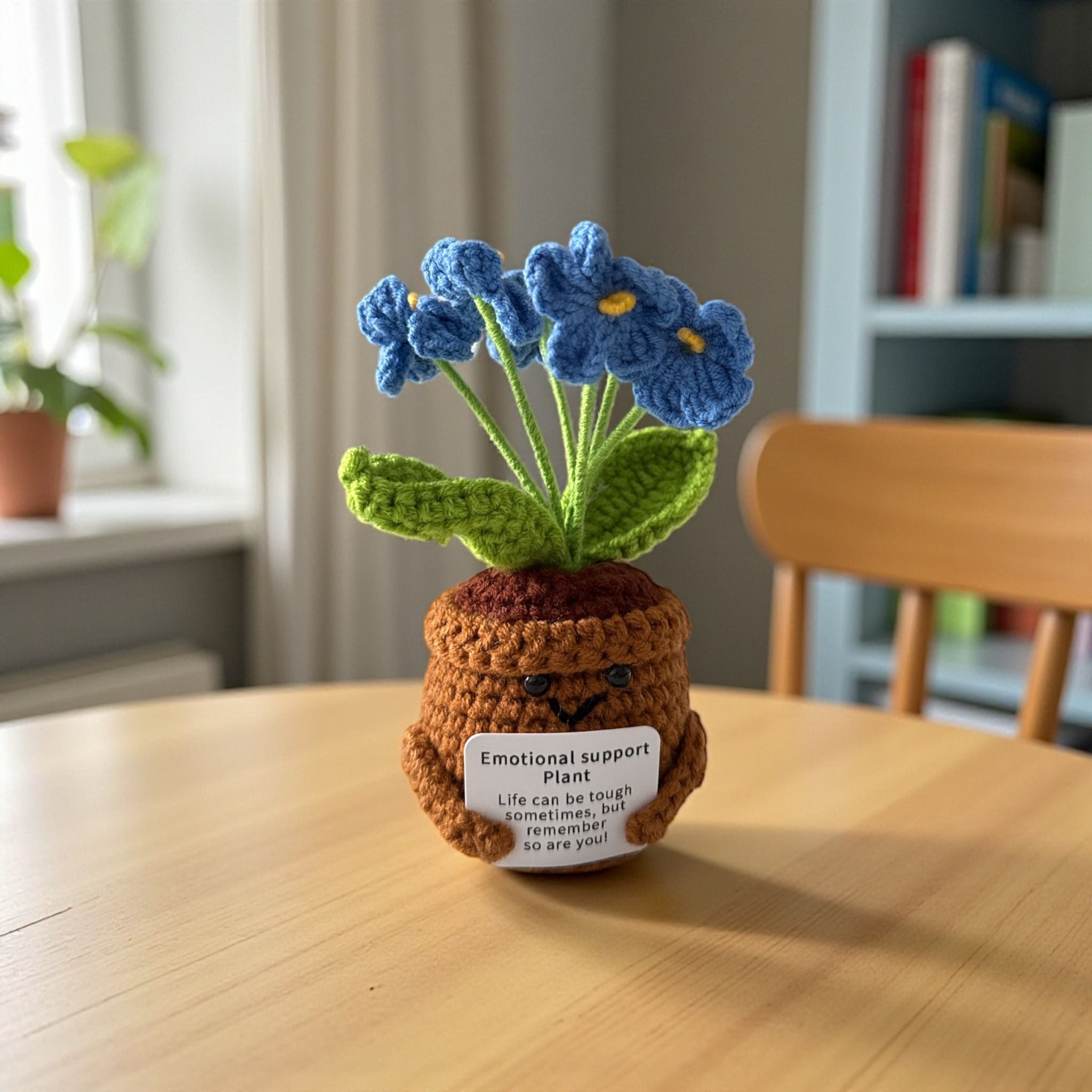 Crocheted emotional support plant on a wooden table with a blurred background