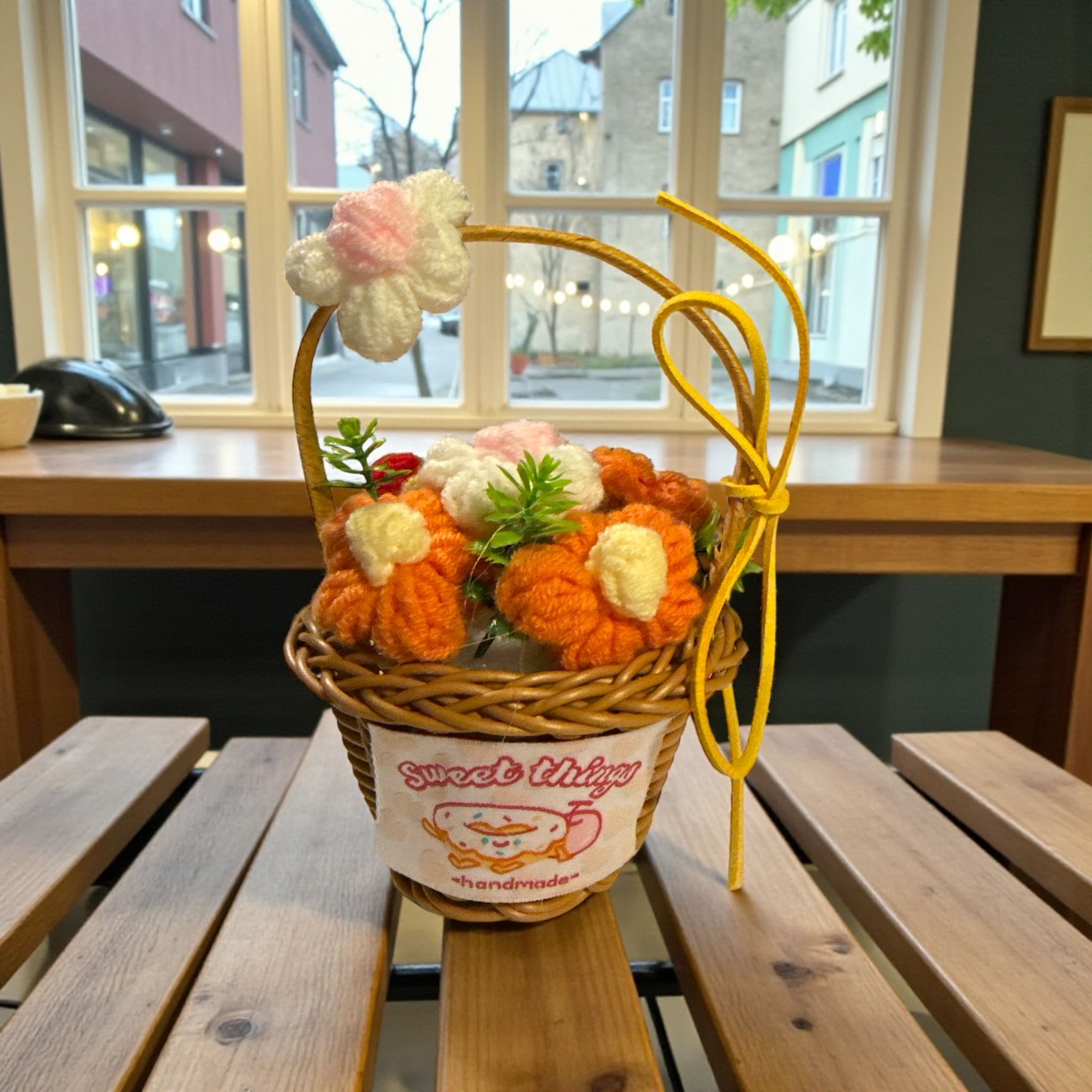 Wicker basket with knitted flowers on a wooden table in a cafe setting
