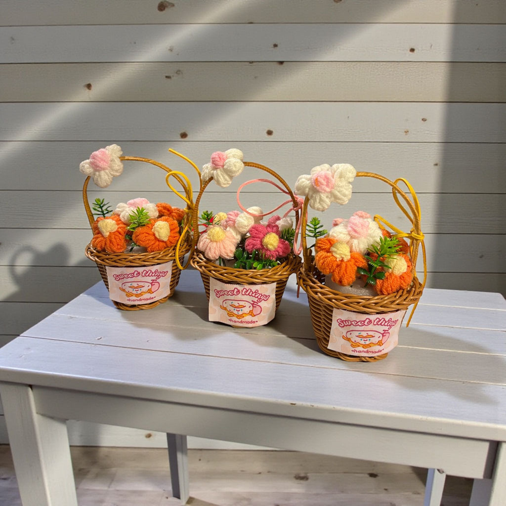 Three decorative flower baskets on a white table with a wooden background