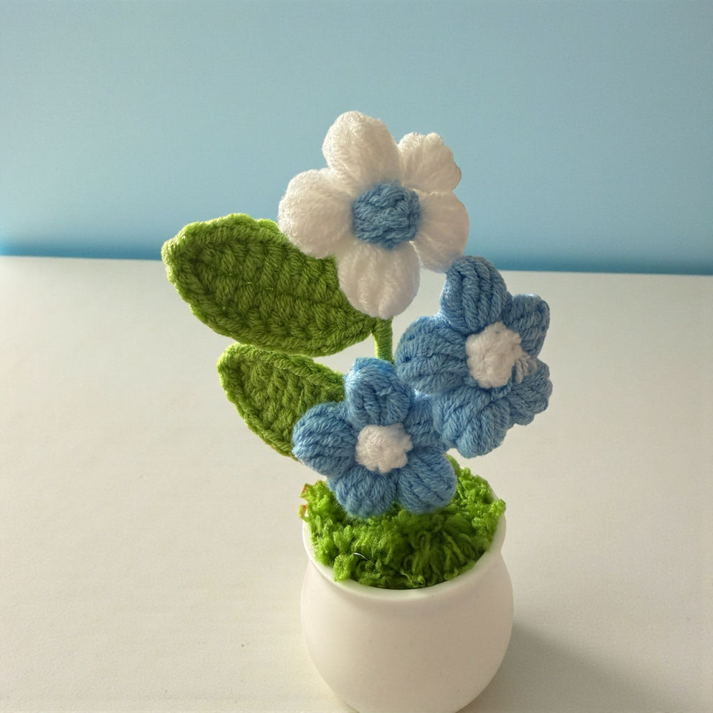 Knitted flowers in a white pot on a light blue background