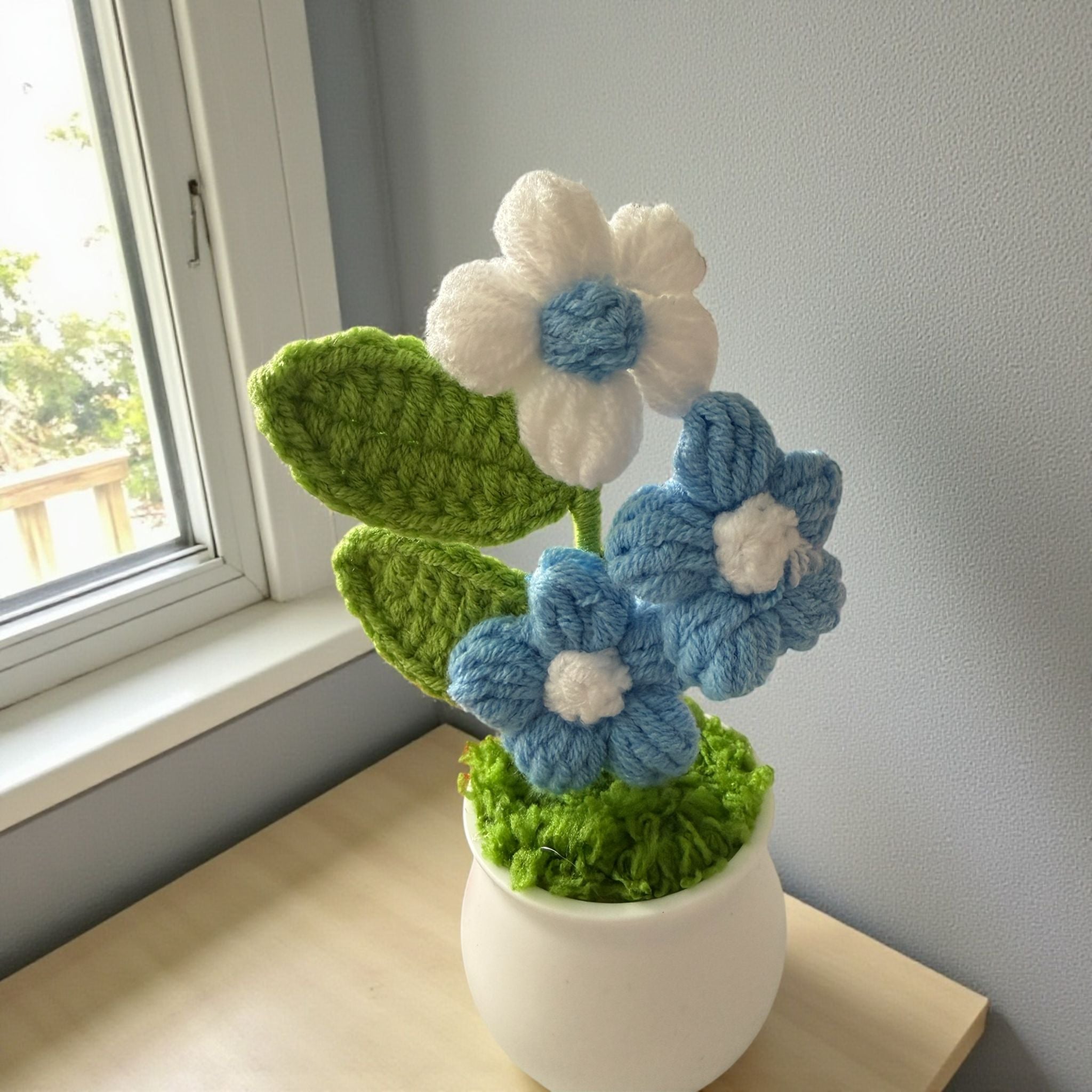 Knitted flowers in a pot on a windowsill