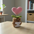 Crocheted plant with a pink heart and smiling face on a table
