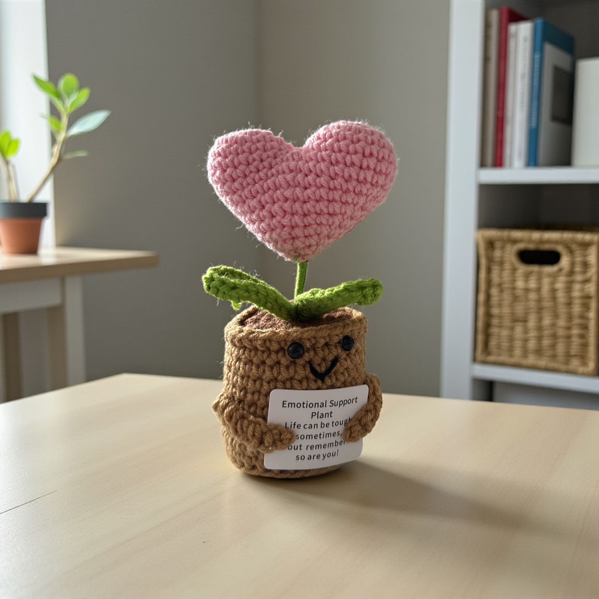 Crocheted plant with a pink heart and smiling face on a table