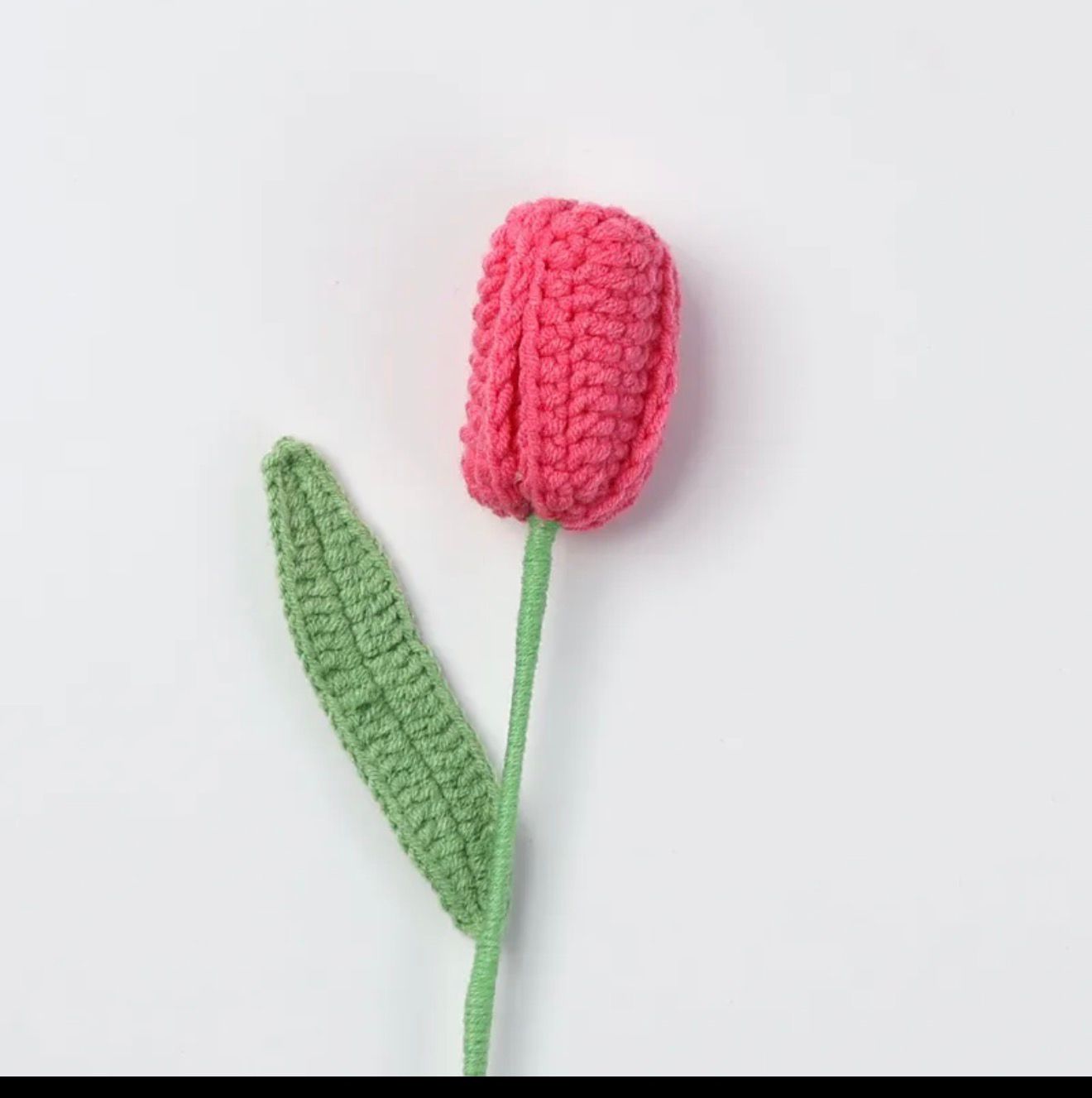 Crocheted pink tulip with green stem on a white background