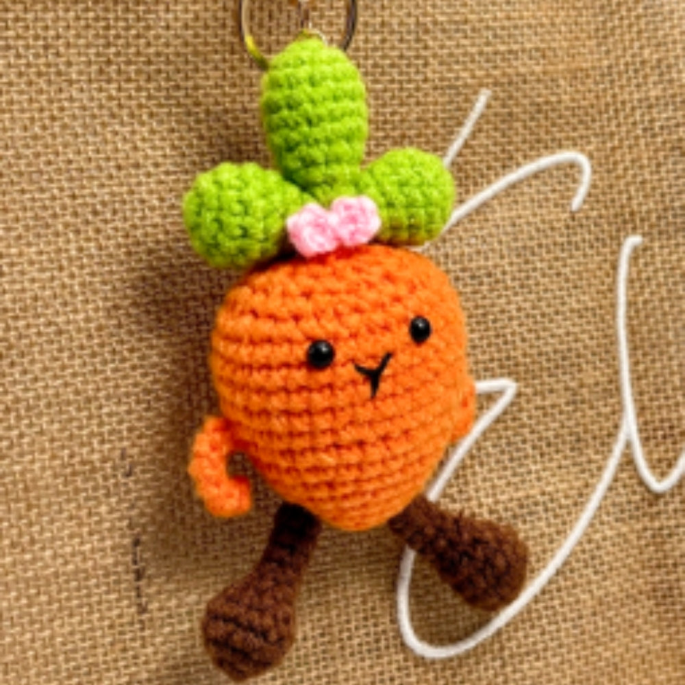 Crocheted carrot keychain with a face on a textured brown background