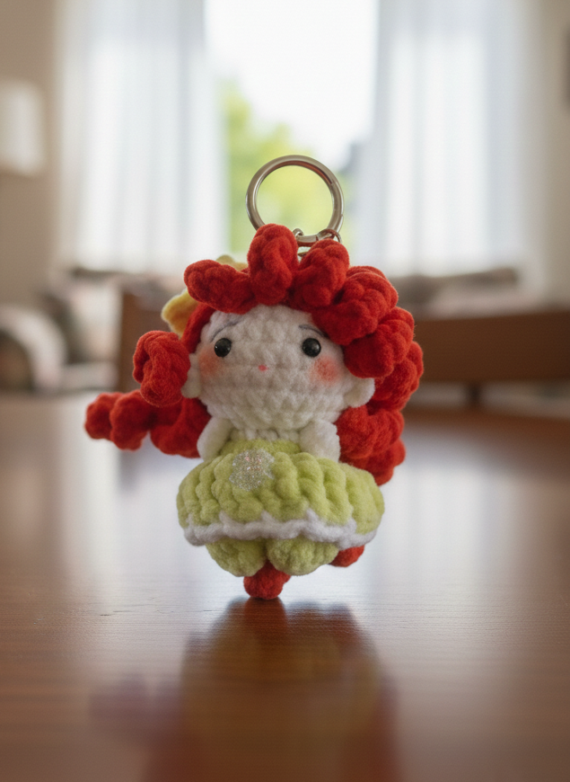 Crocheted keychain with a character wearing a dress on a wooden floor.