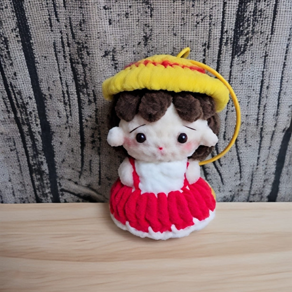 Plush toy with a yellow hat and red dress on a wooden surface with a textured wall background