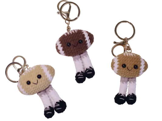 Three small plush keychains shaped like footballs with faces on a white background