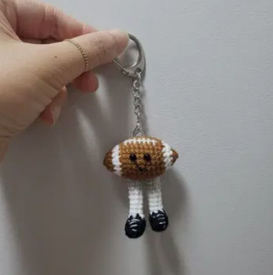 Hand holding a keychain with a small dog figure against a plain background