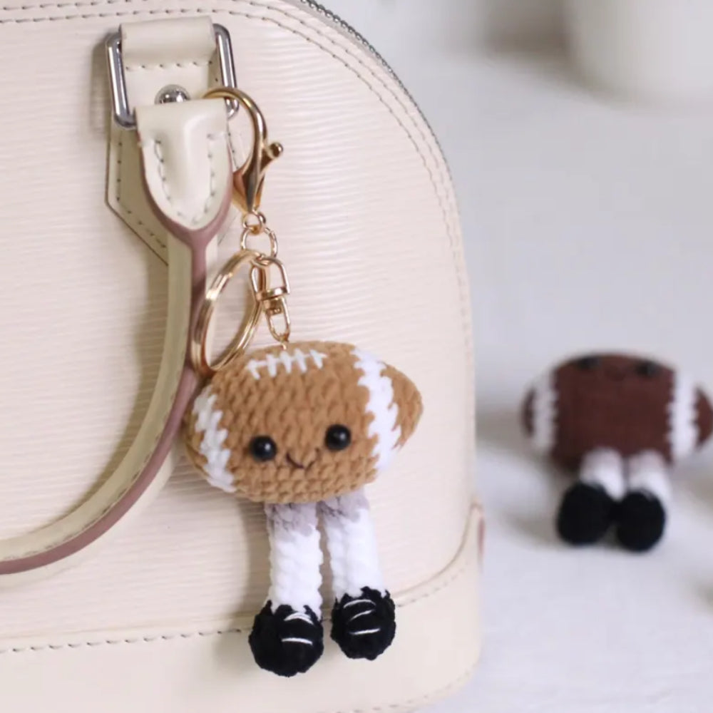 Amigurumi football keychain with a small plush toy on a beige background