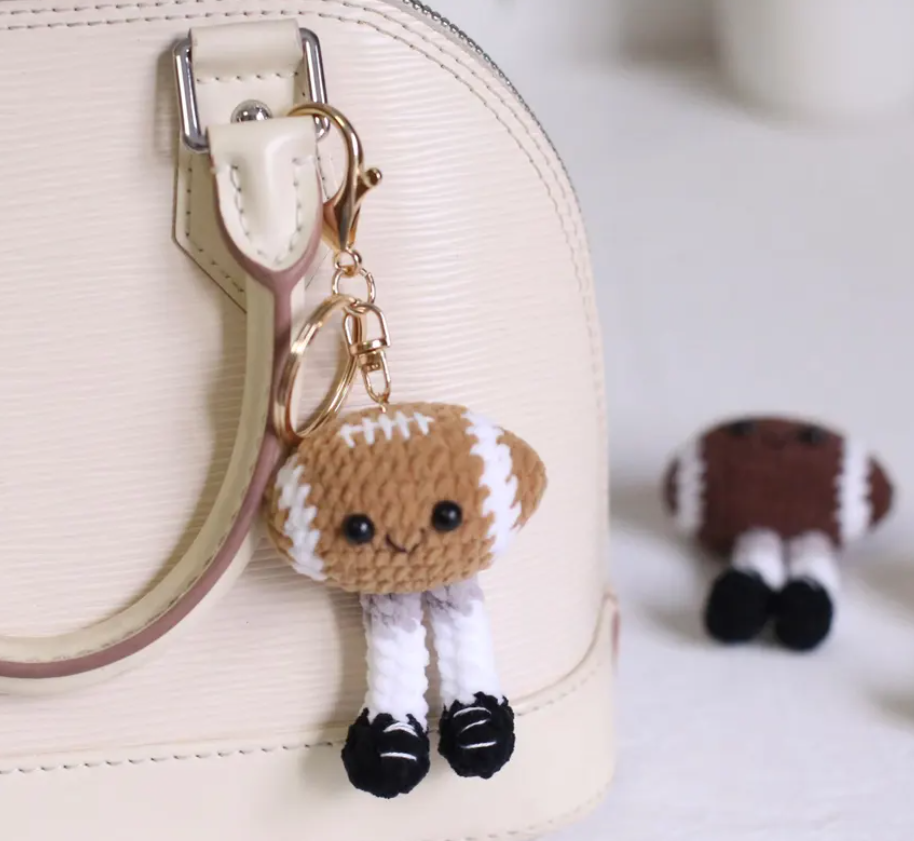 Small brown and white dog-shaped keychain attached to a beige handbag.