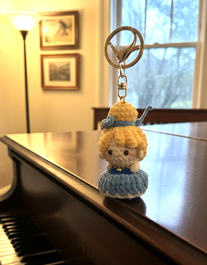 Small crocheted character keychain on a piano