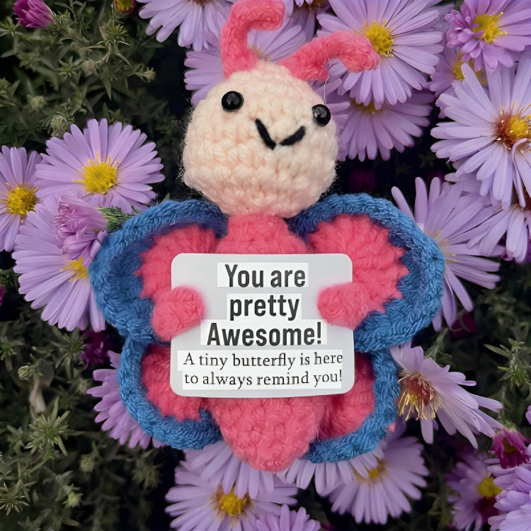 Crocheted butterfly plush toy with a message card surrounded by flowers