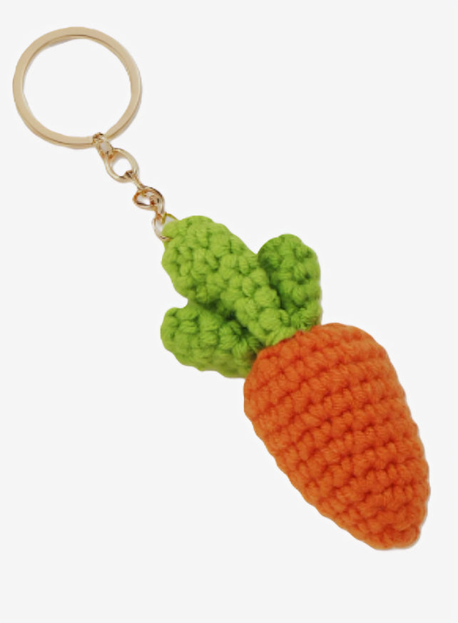 Crocheted carrot keychain with green leaves on a white background