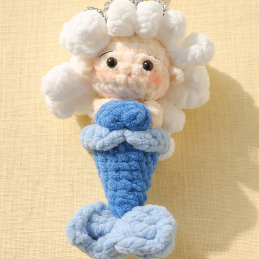Crocheted mermaid toy with white hair and blue tail on a beige background