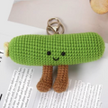 Green crocheted keychain with a face on a piece of paper