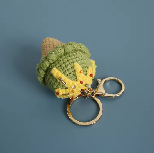 Crocheted dragon keychain with a gold ring on a blue background