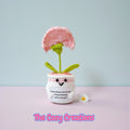 Crocheted flower pot with a pink flower on a light gray background, featuring 'The Cozy Creations' branding.