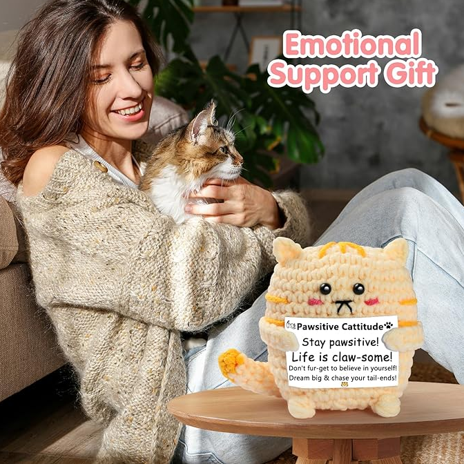 Woman holding a cat with a plush toy on a table, labeled 'Emotional Support Gift'.