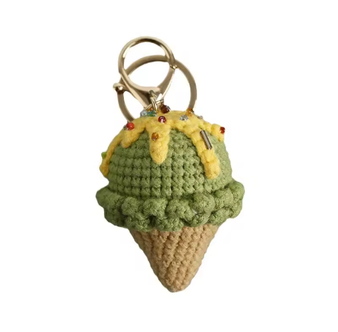 Crocheted ice cream cone keychain with a yellow cherry on top against a white background