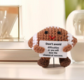 Small plush toy holding a card with text on a light background