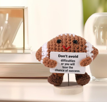 Small plush toy holding a card with text on a light background