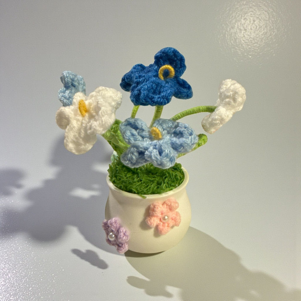 Crocheted flower arrangement in a small pot on a plain background