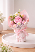 Bouquet of pink flowers wrapped in pink paper on a white plate with a light background