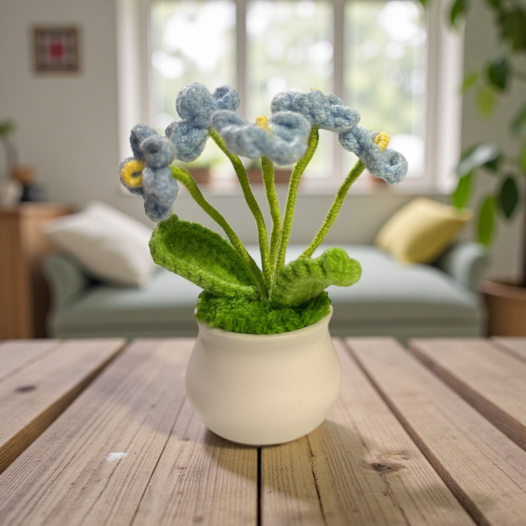 Knitted flower arrangement in a white pot on a wooden table with a blurred indoor background