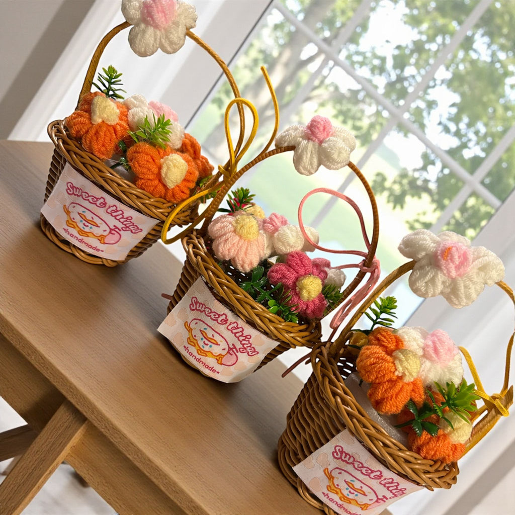 Three small wicker baskets with crocheted flowers and pumpkins on a wooden surface.