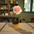 Crocheted flower in a pot on a wooden surface with a blurred background