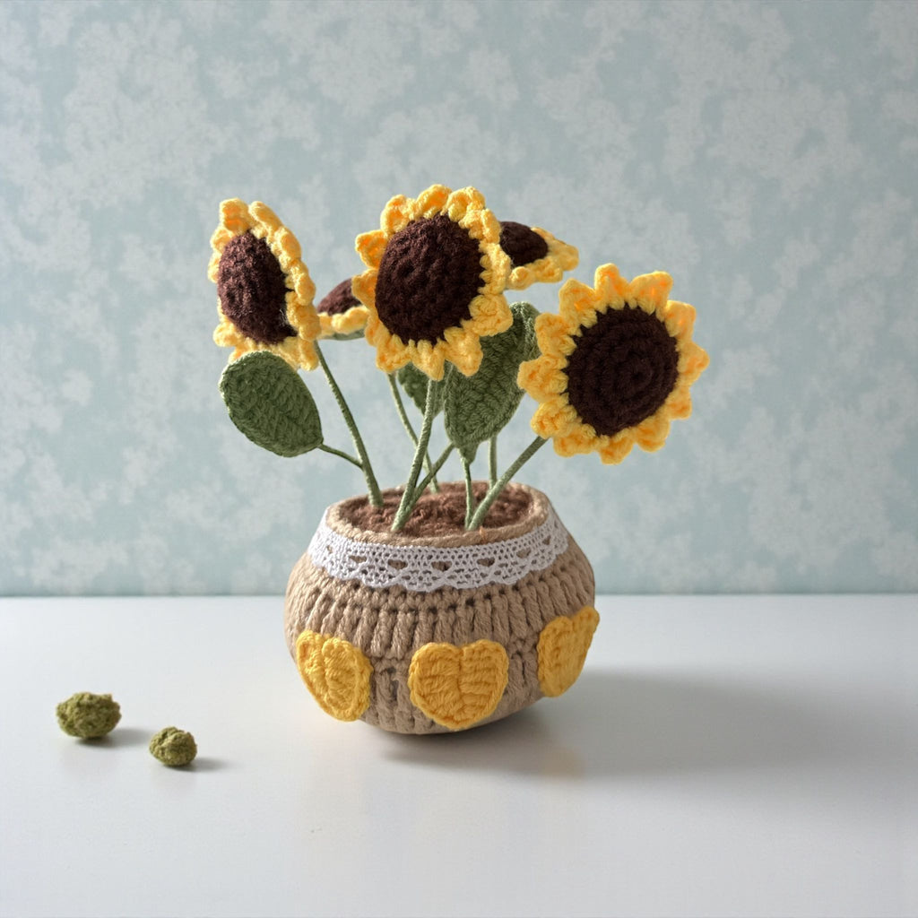 Crocheted sunflowers in a pot on a light surface with a light blue textured background