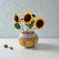 Crocheted sunflowers in a pot on a light surface with a light blue textured background