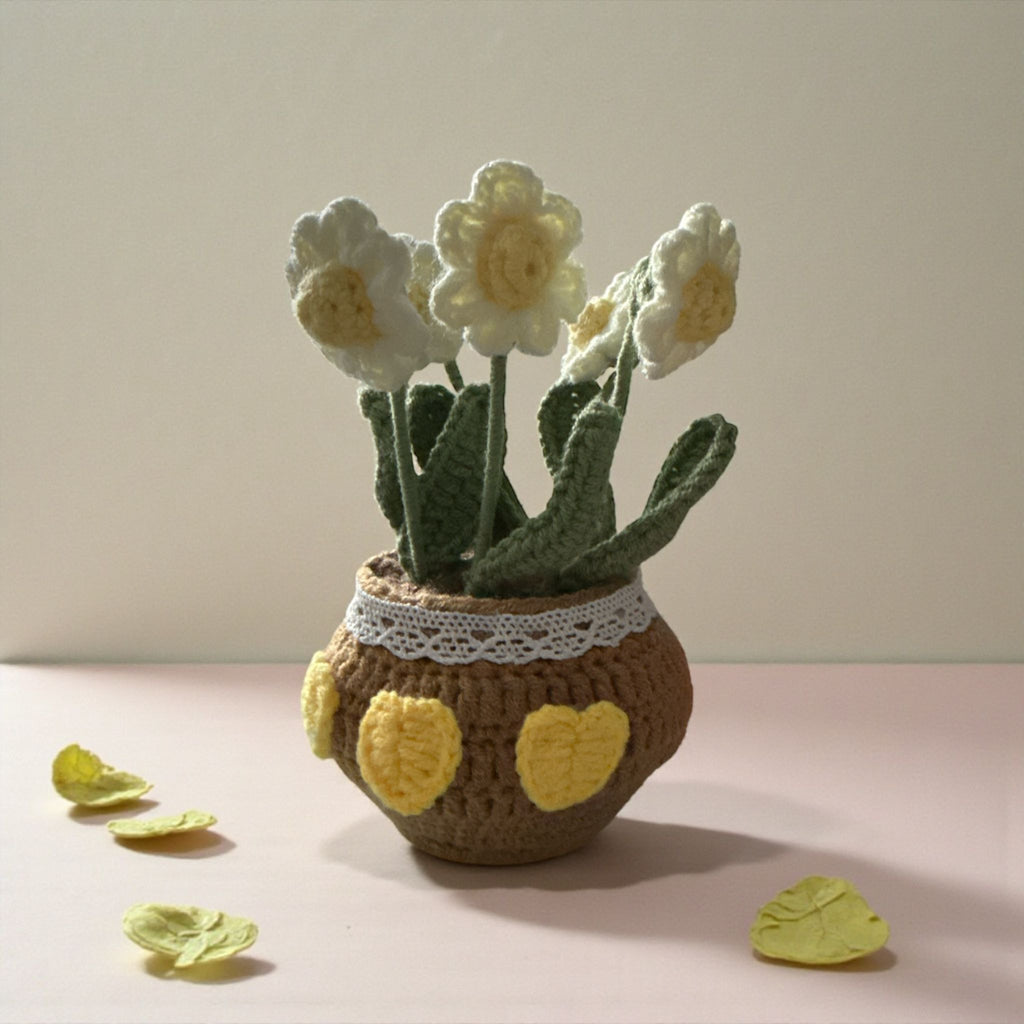 Crocheted flower pot with white and yellow flowers on a beige background