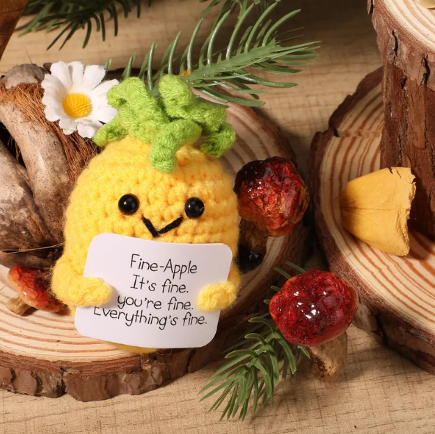 Plush toy pineapple with a sign on a wooden surface with decorative elements