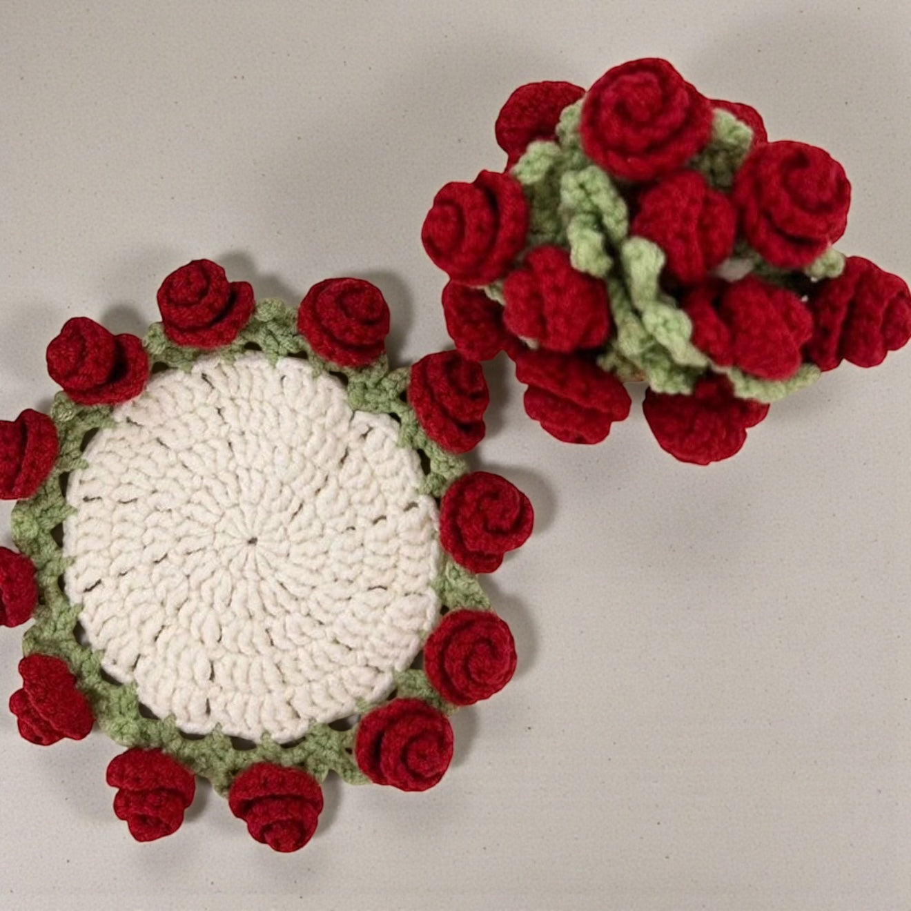 Crocheted coaster with red rose pattern on a light gray background