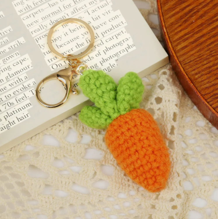 Carrot-shaped keychain with green leaves on a textured surface