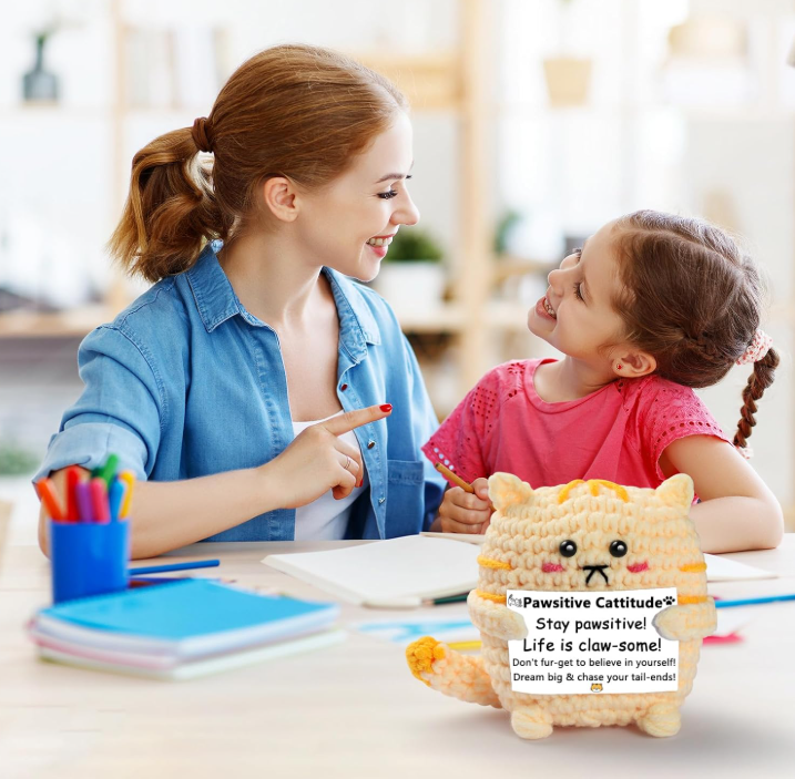 Woman and child sitting at a table with a stuffed animal toy between them.