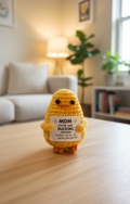 Yellow plush toy with a message card on a wooden table in a living room setting