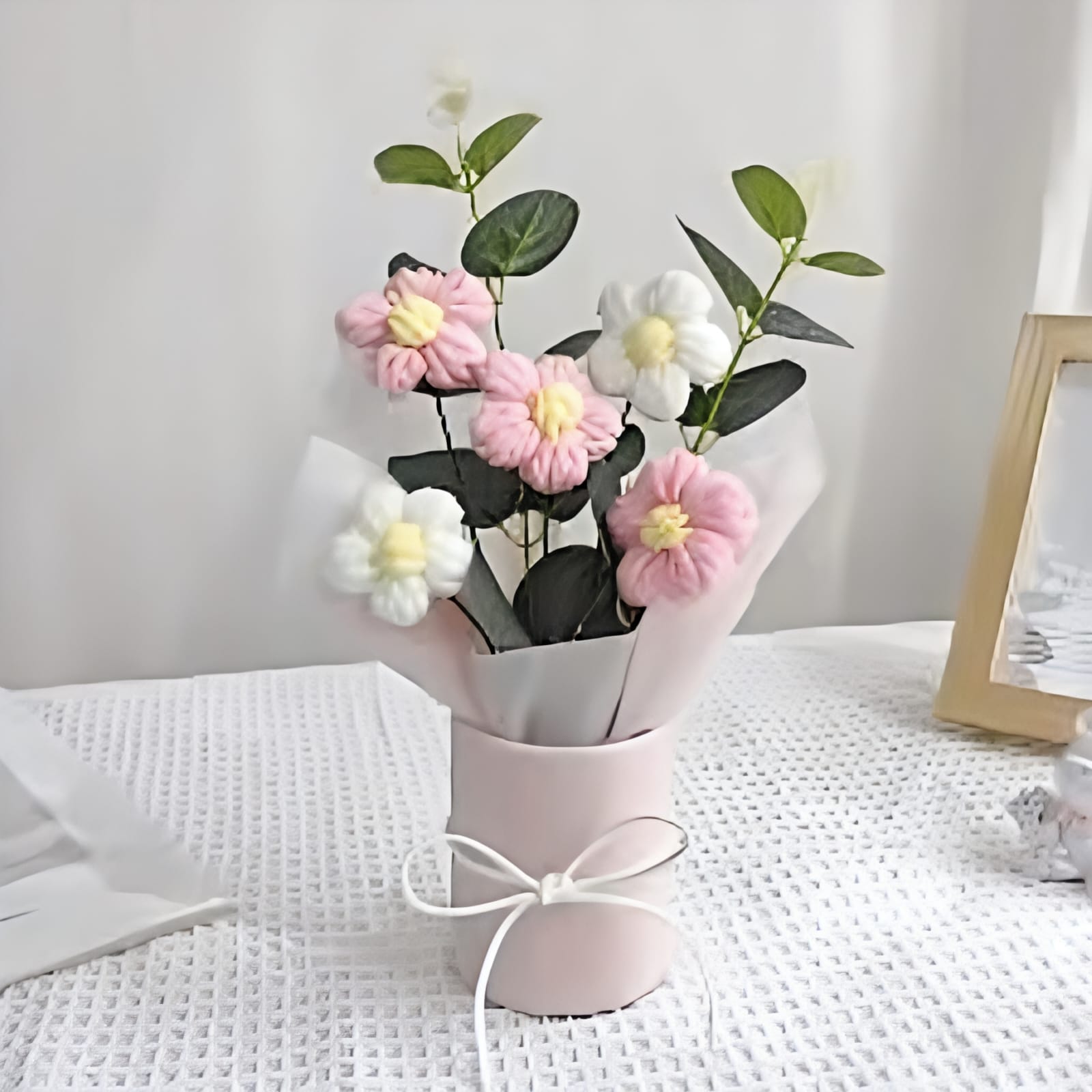 Bouquet of pink and white flowers in a small pink vase on a white surface.
