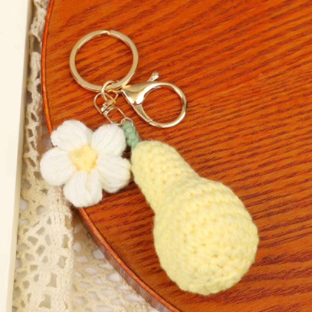 Crocheted pear and flower keychain on a wooden surface