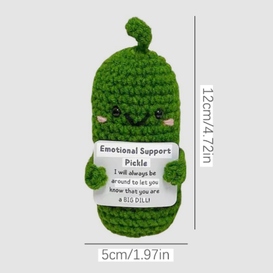 Green plush toy resembling a pickle with a label and measurements on a white background